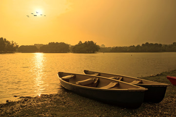 Sunset and old wooden fishing boat near the summer lake shore