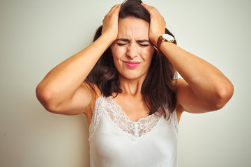 Young beautiful woman wearing t-shirt standing over white isolated background suffering from headache desperate and stressed because pain and migraine. Hands on head.