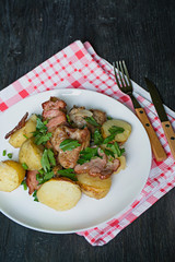 Baked young potatoes with meat and vegetables. Dark wooden background.