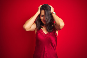 Young beautiful woman wearing sexy lingerie over red isolated background suffering from headache desperate and stressed because pain and migraine. Hands on head.