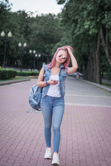 Young Urban Woman With Modern Hairstyle Using Smartphone Walking In Street In An Urban Park