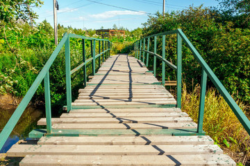Obraz premium wooden bridge over a small river leading to a technological structure