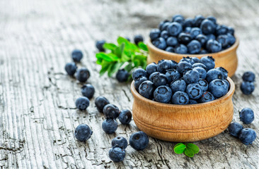 Juicy and fresh blueberries with green leaves on rustic table. Bilberry on wooden Background. Blueberry antioxidant. Concept for healthy eating and nutrition