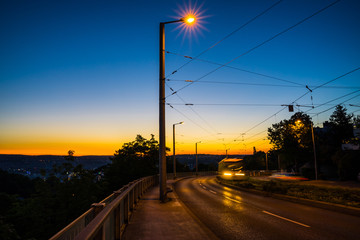 Fototapeta na wymiar Germany, Illuminated fast driving public transport tramway on rails driving up from stuttgart city to ostfildern in magical dawning twilight mood after sunset in summer