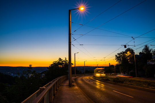Germany, Illuminated fast driving public transport tramway on rails driving up from stuttgart city to ostfildern in magical dawning twilight mood after sunset in summer