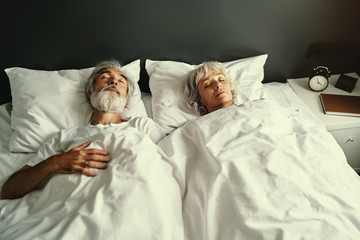 Senior family couple sleeping together in bed.