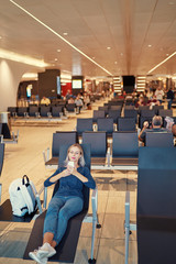 Travel and technology. Pretty young woman using smartphone while sitting at airport terminal...