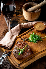 Grilled chuck beef steak with wine, knife and fork on a wooden Board. Whole roast piece of meat, close up and rustic style