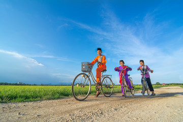 happy young local boy riding old bicycle at paddy field