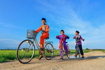 happy young local boy riding old bicycle at paddy field