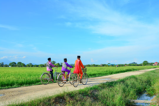happy young local boy riding old bicycle at paddy field