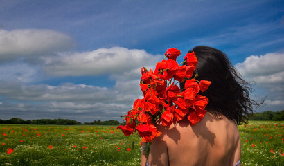 The girl with a bouquet of poppies in the field.