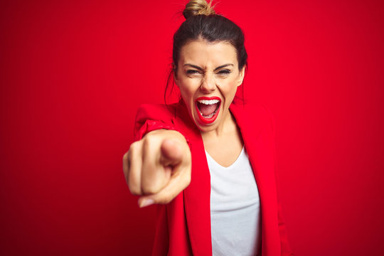 Young beautiful business woman standing over red isolated background pointing displeased and frustrated to the camera, angry and furious with you