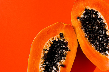 Fresh papaya exotic tropical fruit on orange background. Sun day light illumination. Minimalistic summer flat lay wallpaper. Creative food concept. Copy space template. Bold colors.