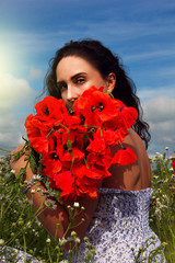 The girl with a bouquet of poppies in the field.