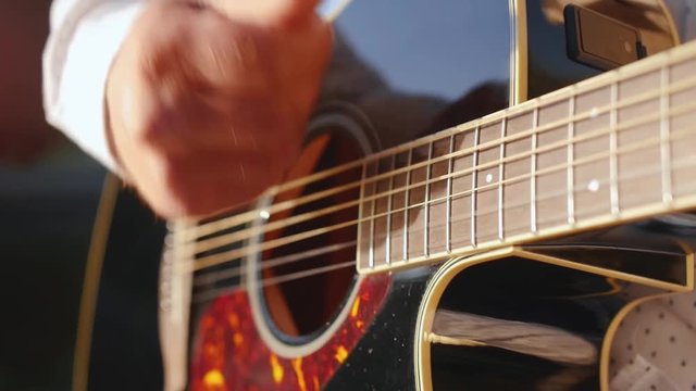 Human hands plays guitar. Guitarist touching guitar strings. Close up shot.