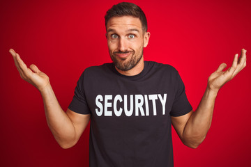 Young safeguard man wearing security uniform over red isolated background clueless and confused...