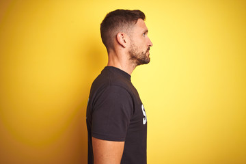 Young safeguard man wearing security uniform over yellow isolated background looking to side, relax...