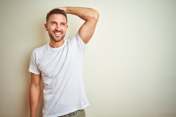 Young handsome man wearing casual white t-shirt over isolated background smiling confident touching...