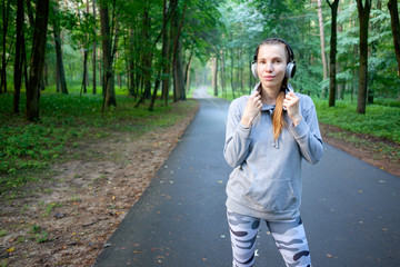 Portrait of young smiling woman resting after jogging and listening to music. Healthy sports lifestyle. Fitness and workout outdoor.