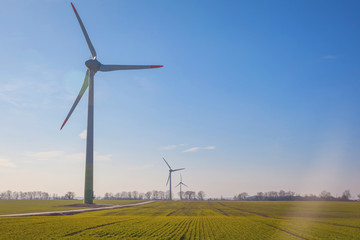 wind turbine on green field with sun flare blue sky background