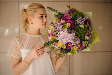 Girl holding a spring bouquet of tender green, yellow and violet flowers