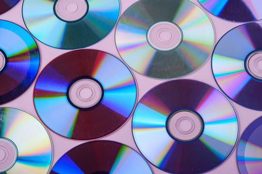 CD DVD compact disc disk dispersion refraction reflection of light colors texture on pink background