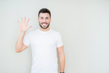 Young handsome man wearing casual white t-shirt over isolated background showing and pointing up with fingers number five while smiling confident and happy.