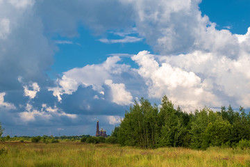 Bright landscape with cumulus clouds and a red church with a bell tower.