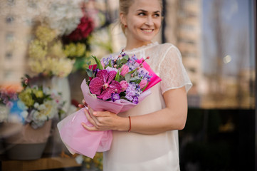 Fototapeta premium Smiling girl holding a bouquet of crimson orchid and violet hyacinth
