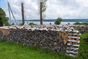 A large woodpile of birch wood and a view of the Volga River.