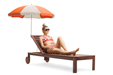 Young beautiful woman in bikini on a sunbed with umbrella