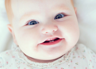 top view of infant baby girl, smilyng with her first two teeth