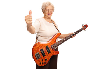Happy senior woman with an electric guitar showing thumbs up