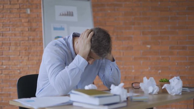 young working man is very tired and overworked because of stressful and pressure business tasks siting at the table 4K