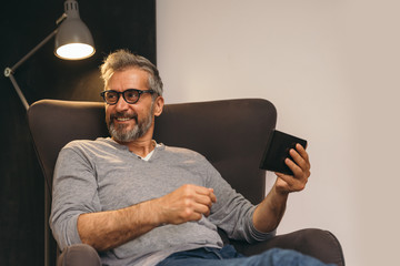 middle aged man using tablet while sitting in sofa at his home