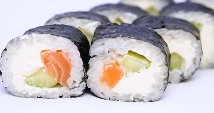 One or more maki rolls in a row with salmon, avocado, tuna and cucumber isolated on white background. Fresh hosomaki pieces with rice and nori. Closeup of delicious japanese food with sushi roll.