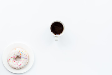 donut and black coffee with copy space. Cup of black coffee with donut on a plate on white table, top view, flat lay. Delicious breakfast.
