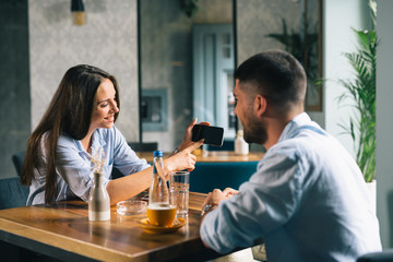young couple in cafe bar drinking coffee and using smartphone