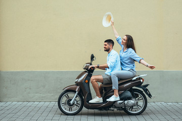 Happy couple on scooter driving outdoor in the city
