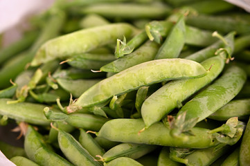 Closed green pea pods in a pile.