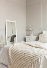 Cozy cream colored woolen blanket on king size bed in bright bedroom