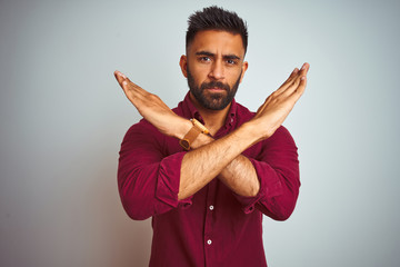 Young indian man wearing red elegant shirt standing over isolated grey background Rejection...
