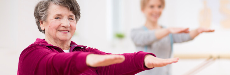 Panoramic view of senior grey woman exercising at hospital physiotherapy center