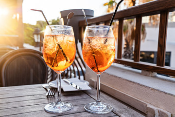 Two wine glass of cold cocktail Aperol spritz on background of restaurant. Traditional Italian...