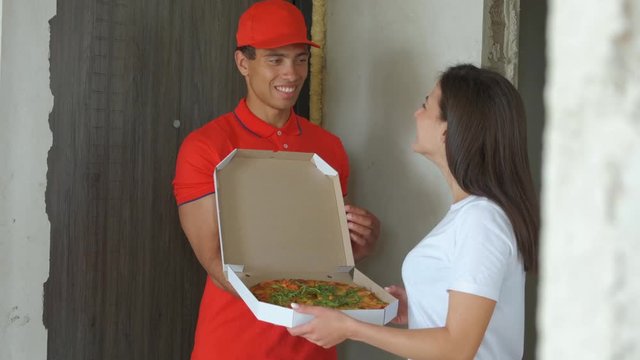 Young handsome pizza delivery boy. Pretty girl got pizza. concept delivery food.