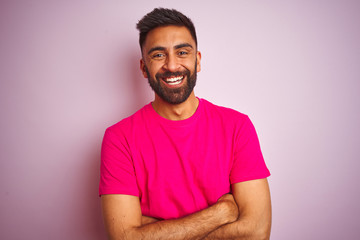 Young indian man wearing t-shirt standing over isolated pink background happy face smiling with...