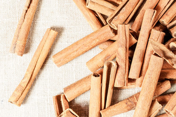Closeup detailed photo - Heap of natural cinnamon bark sticks on linen tablecloth.
