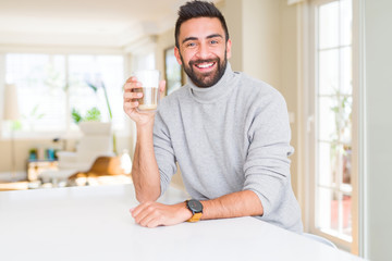 Handsome hispanic man drinking a cup of coffee with a happy face standing and smiling with a confident smile showing teeth