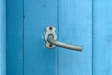 Nahaufnahme eines Türgriffs an einer blauen Holztür